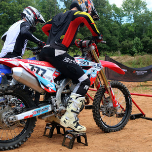 Two motocross racers practicing their starts with Holeshot gates. The rider in focus is using Adjustable Motocross Starting Blocks by Risk Racing.
