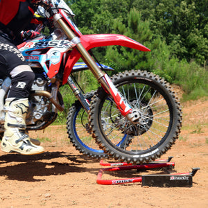 Outdoor picture of two MX riders practicing their starts using Holeshot Pro Gates from a side view